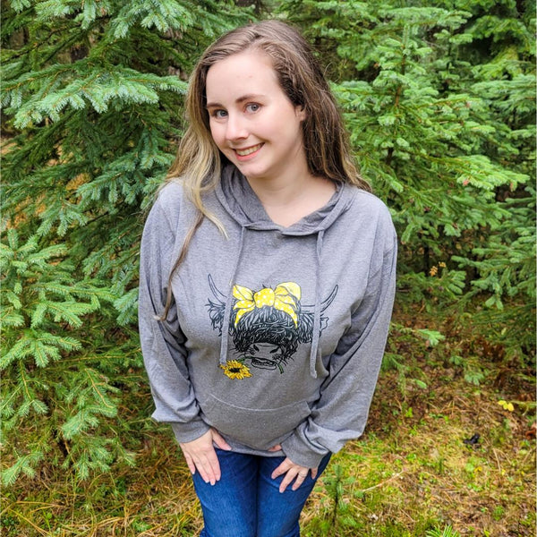 Women in grey hoodie with a highland cow on it