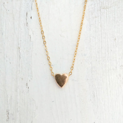 Small gold-colored heart pendant on a chain on a white background