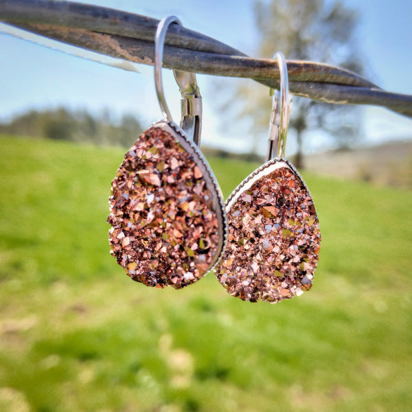 Rose teardrop dangles displayed on a wire outside.