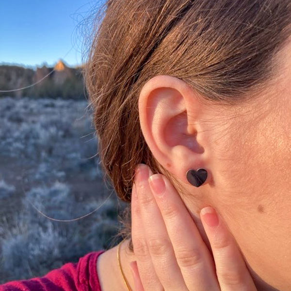 A girl wearing small silver-colored heart stud earrings